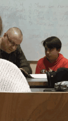 a boy in a red champion sweatshirt sits in front of a white board that says level a