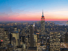 a city skyline with the empire state building lit up at night