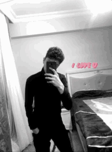 a man taking a picture of himself in front of a bed with the words i love u on the wall