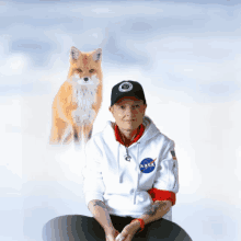 a man wearing a nasa hoodie sits next to a fox