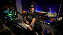 a man in a proud skeptic shirt sits at a desk in front of a microphone with the word run above him