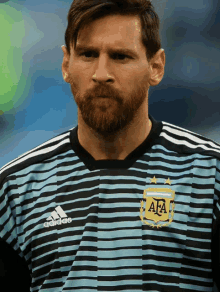 a man with a beard wears a striped adidas shirt