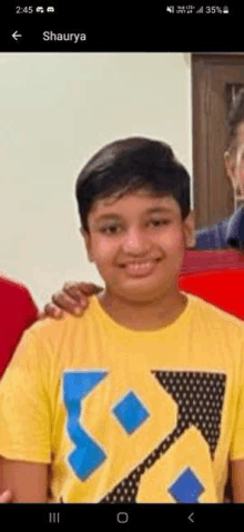 a young boy wearing a yellow t-shirt with a blue triangle on it