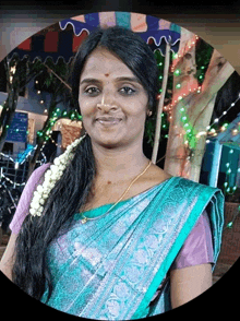 a woman in a blue and purple sari smiles for a picture