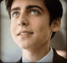 a close up of a young man wearing a suit and tie .