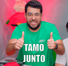 a man wearing a green shirt that says tamo junto giving two thumbs up