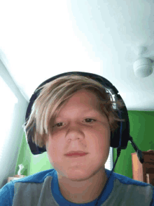 a young boy wearing headphones is looking at the camera