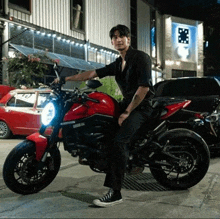 a man sits on a red ducati motorcycle in front of a building