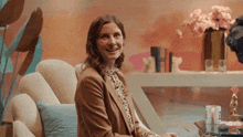 a woman is sitting on a couch smiling and looking at the camera .