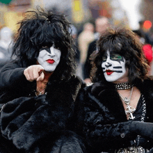 a man in a black fur coat is pointing at another man in a black fur coat