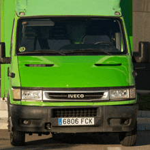 a green iveco truck is parked in front of a green wall