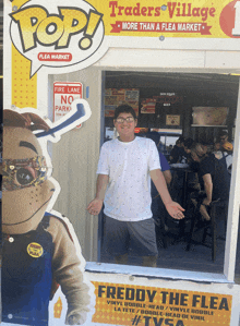 a man stands in front of a pop sign for traders village