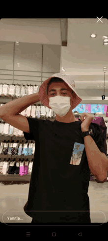 a man wearing a face mask and a pink hat stands in front of a store