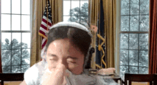 a woman wearing headphones wipes her nose with a napkin