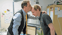 a man kissing another man on the cheek in front of a calendar