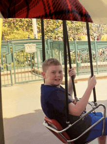 a boy is sitting on a swing in front of a sign that says exit