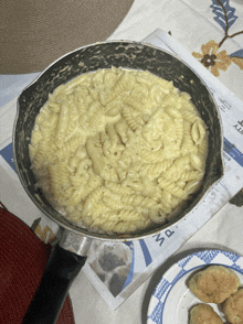 a pan of macaroni and cheese sits on a table next to a newspaper that says ' kitty ' on it