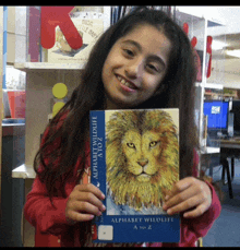 a young girl is holding a book titled alphabet wildlife a to z