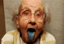 an elderly woman with glasses and a blue tongue sticking out of her mouth .