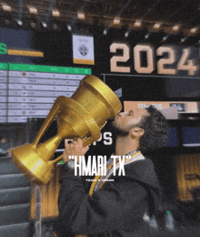 a man holding a trophy with the year 2024 behind him