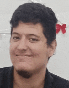 a close up of a man 's face with a red bow on his ear .