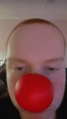 a man with a red clown nose is looking at the camera