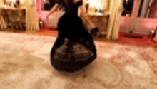 a woman in a long black dress is dancing on a rug in a room .