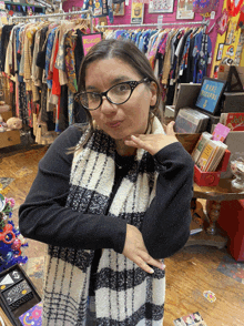 a woman wearing glasses and a scarf in a store with a sign that says ' i love you ' on it