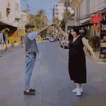 a man and a woman are dancing on a street in front of a sign that says ' chinese ' on it