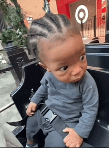 a baby with braids is sitting in a chair with a target sign in the background