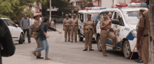 a group of police officers are standing in front of a white vehicle with the number 14 on the side