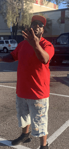 a man wearing a red shirt and a red hat is standing in a parking lot