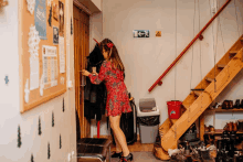 a woman in a red dress is standing in a hallway next to a green exit sign