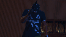 a man wearing a black shirt that says ammassa holds a gun