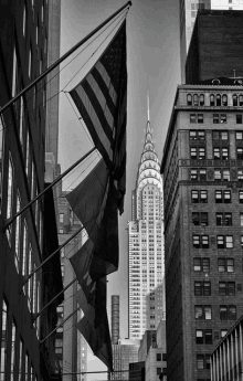 a black and white photo of the chrysler building with flags in the foreground