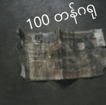 a pile of money is sitting on a table with the words `` 100 myanmar dollars '' written on it .