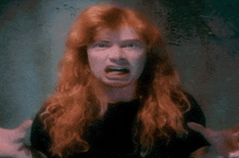 a man with long red hair is making a funny face with his mouth open .