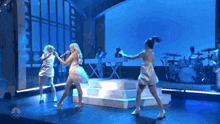 a group of women are dancing on a stage while a man plays a keyboard .