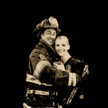 a black and white photo of a fireman and a woman hugging each other .