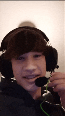 a boy wearing headphones and a microphone looks at the camera