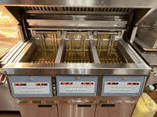 a stainless steel deep fryer is filled with oil in a kitchen .