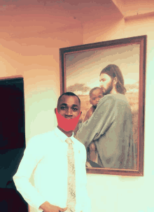 a man wearing a red mask is standing in front of a painting of jesus holding a baby