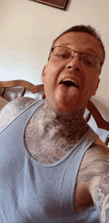 a man wearing glasses and a blue tank top has a tattoo on his neck