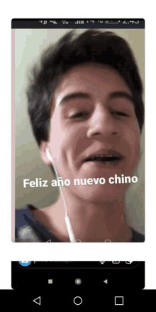 a phone screen shows a man wearing earbuds and the words feliz ano nuevo chino