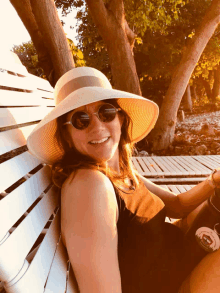 a woman wearing a hat and sunglasses sits on a white chair