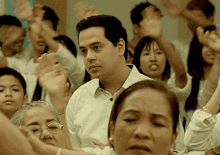 a man in a white shirt stands in front of a crowd of people