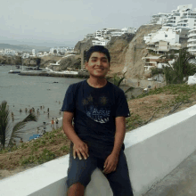 a boy wearing an aussie t-shirt sits on a wall