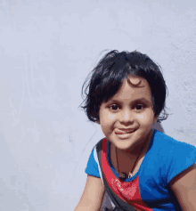 a little girl wearing a blue shirt with a heart on it smiles