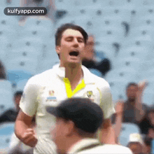 a man in a white shirt is standing in front of a crowd in a stadium with his fist in the air .