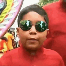 a young boy wearing sunglasses and a red shirt is standing in a crowd .